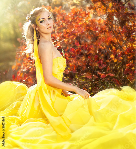 Photo: Young beautiful girl in a yellow dress in the woods Young beautiful girl in a yellow dress in the woods