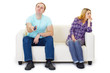 Husband and wife in a quarrel sit on couch watching TV