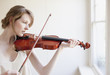 Woman playing violin near window