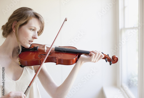 Photo: Woman playing violin near window Woman playing violin near window