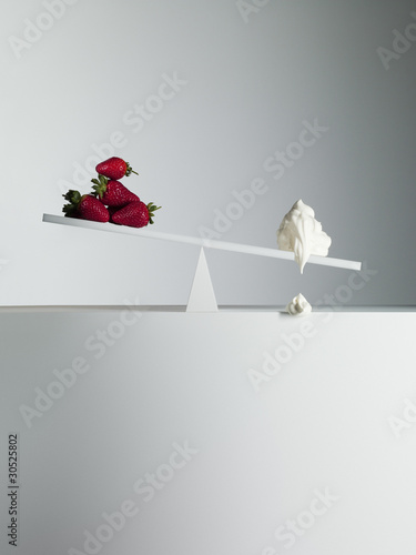 Photo: Dripping cream tipping seesaw with strawberries on opposite end Dripping cream tipping seesaw with strawberries on opposite end