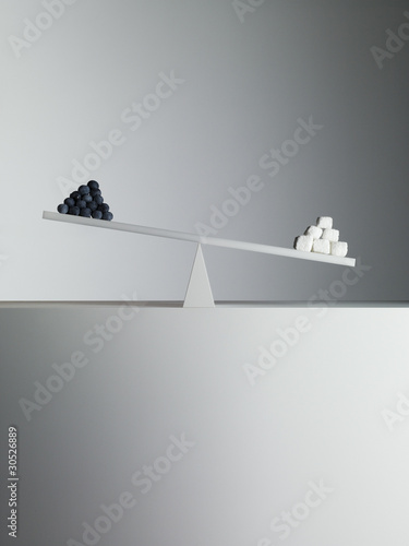 Photo: Sugar cubes tipping seesaw with blueberries on opposite end Sugar cubes tipping seesaw with blueberries on opposite end