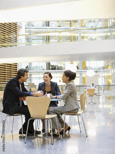 Foto: Smiling business people having a meeting at cafeteria table Smiling business people having a meeting at cafeteria table