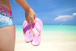 asian girl on a beach holding slipper