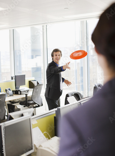 Foto: Businessman throwing plastic disc in office Businessman throwing plastic disc in office