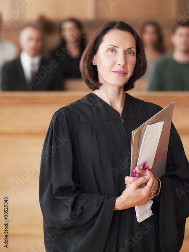 Photo: Confident judge holding file in courtroom Confident judge holding file in courtroom