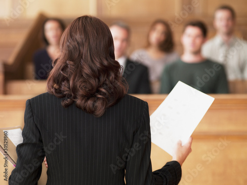 Photo: Lawyer holding document and speaking to jury in courtroom Lawyer holding document and speaking to jury in courtroom