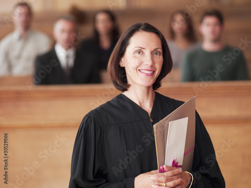 Photo: Smiling judge holding file in courtroom Smiling judge holding file in courtroom