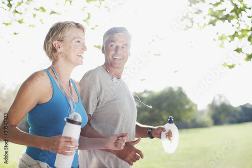 Photo: Couple jogging together with water bottles Couple jogging together with water bottles