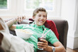 Teenage boy with snacks holding remote control
