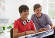 Photo: Teenage boy watching friend play electronic piano keyboard Teenage boy watching friend play electronic piano keyboard
