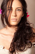 Portrait of young brunette woman with flower in curly hair