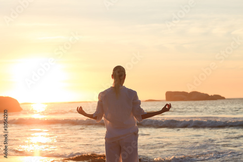 Photo: Woman practicing yoga during the sunset Woman practicing yoga during the sunset