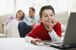 Boy using laptop with parents in background