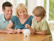 Parents watching son putting coin into piggy bank
