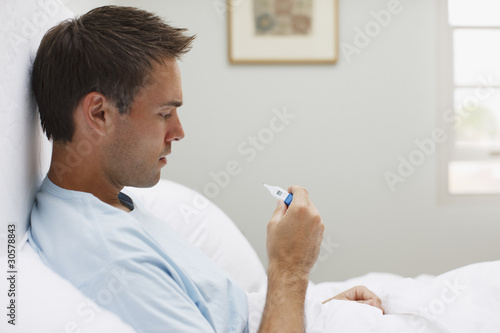 Photo: Sick man taking temperature with digital thermometer Sick man taking temperature with digital thermometer