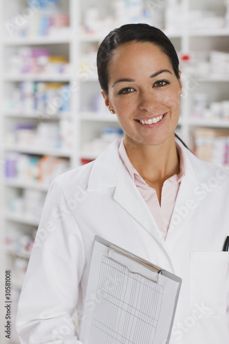 Foto: Smiling pharmacist in drug store holding clipboard Smiling pharmacist in drug store holding clipboard