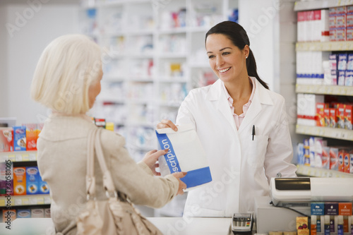 Photo: Pharmacist handing customer prescription in drug store Pharmacist handing customer prescription in drug store