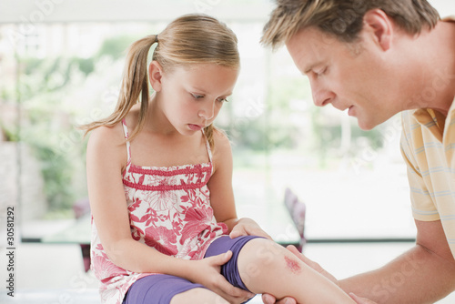 Foto: Father tending to daughter?s scraped knee Father tending to daughter?s scraped knee