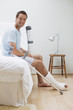 Man with broken leg sitting on bed