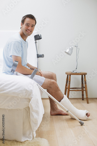 Photo: Man with broken leg sitting on bed Man with broken leg sitting on bed