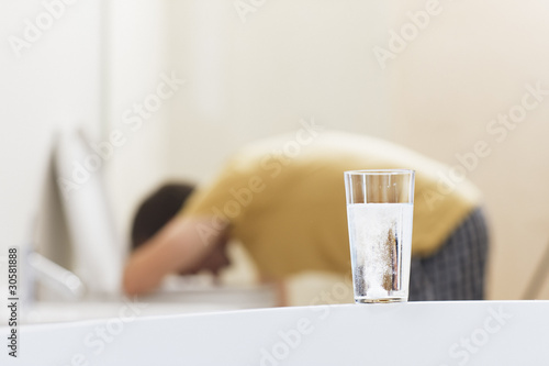Photo: Glass of dissolving medicine with vomiting man in background Glass of dissolving medicine with vomiting man in background