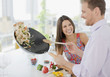 Woman watching husband flipping stirfry in the kitchen