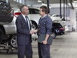 Businessman shaking hands with mechanic in auto repair shop