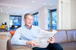 Foto: Man reading newspaper on couch Man reading newspaper on couch