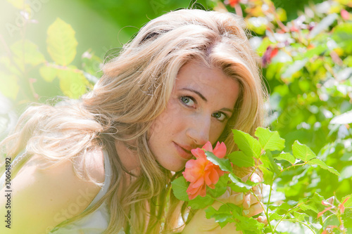 Foto: Frau riecht an einer Rose im Garten Frau riecht an einer Rose im Garten