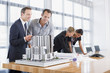 Business people looking at blueprints and model building