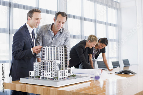 Foto: Business people looking at blueprints and model building Business people looking at blueprints and model building