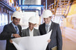 Business people reviewing blueprints in factory
