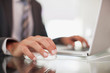 Businessman using computer mouse and typing on laptop