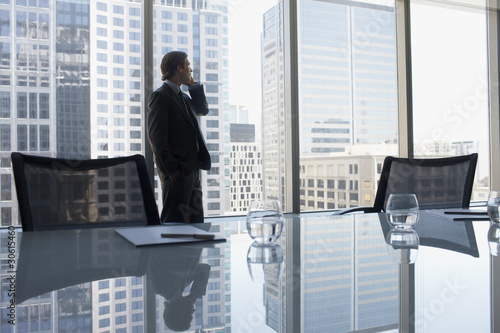 Photo: Businessman talking on cell phone in conference room Businessman talking on cell phone in conference room