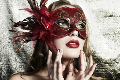Photo: Beautiful young woman in a red mysterious venetian mask Beautiful young woman in a red mysterious venetian mask