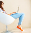 Young woman using laptop on ball chair