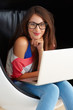 Young woman in egg chair using laptop