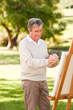 Elderly man painting in the park Elderly man painting in the park