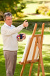 Elderly man painting in the park Elderly man painting in the park