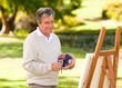 Elderly man painting in the park Elderly man painting in the park
