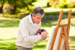 Elderly man painting in the park Elderly man painting in the park