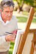 Elderly man painting in the park Elderly man painting in the park