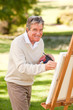 Elderly man painting in the park Elderly man painting in the park