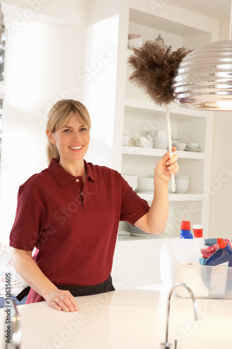 Photo: Cleaner Working In Domestic Kitchen With Feather Duster Cleaner Working In Domestic Kitchen With Feather Duster