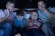 Family Watching Scary Programme On TV Sitting On Sofa Together
