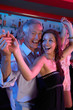 Senior Man Dancing With Younger Woman In Busy Bar
