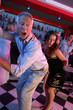 Senior Man Dancing With Younger Woman In Busy Bar