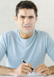 Man holding pen and furrowing brow