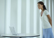 Woman standing, looking down at laptop